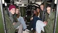Eine Gruppe von jungen Frauen sitzen im Innenraum eines Militärfahrzeugs.