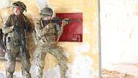 Zwei Soldaten stehen an einer Wand, sie schauen in verschiedenen Blickrichtungen