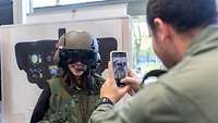 Mann macht ein Foto von einer Frau mit einem Pilotenhelm auf 