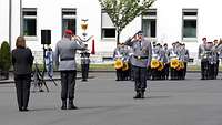 Zwei Soldaten stehen sich gegenüber und grüßen. Im Hintergrund weitere Soldatinnen und Soldaten.