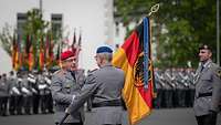 EIn Soldat übergibt einem anderem Soldaten eine Fahne