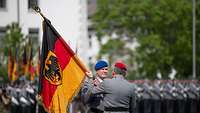 Ein Soldat übergibt einem anderen Soldaten ein Fahne