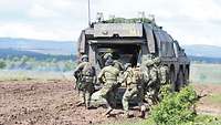 Eine Gruppe Soldaten nähert sich der hinteren Einstiegsluke eines Sanitätsfahrzeug vom Typ GTK Boxer