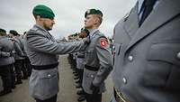 Ein Soldat korrigiert bei einem der in Reihe angetretenen Rekruten den Sitz der Krawatte