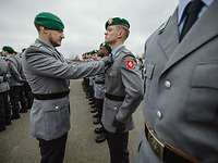 Ein Soldat korrigiert bei einem der in Reihe angetretenen Rekruten den Sitz der Krawatte