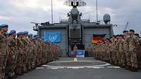 Mehrere Soldaten in Formation stehen sich auf dem Flugdeck eines Schiffes gegenüber
