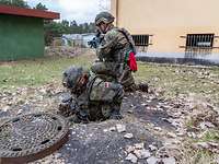 Zwei Soldaten klettern auf einem Truppenübungsplatz in die Kanalisation. Sie sind bewaffnet.