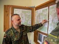 Zwei Soldaten der Bundeswehr unterhalten sich vor einer Lagekarte. Ein Soldat ist Oberstabsfeldwebel