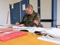 Ein Soldat arbeitet konzentriert an Karten. Er trägt eine Armbinde mit der Aufschrift Range Control