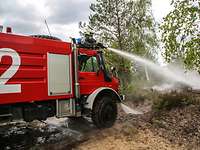 Ein Feuerwehrfahrzeug löscht einen Brand in der Natur. 