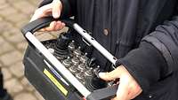 Two hands holding a large black remote control with silver and black switches.