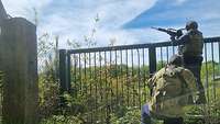 Angriff auf das Munitionslager Zwei bewaffnete Personen versuchen über einen Zaun zu klettern
