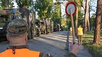 Ein Soldat gibt mit einer Winkerkelle das Zeichen zur Abfahrt.