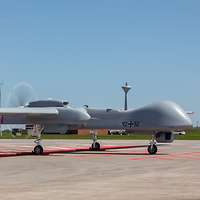 Ein unbemanntes Flugzeug steht mit rotierendem Propeller auf einer Start- und Landebahn