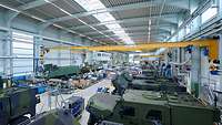 Eine riesige Werkstatthalle mit militärischen Fahrzeugen darin