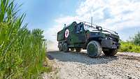 Ein Militärfahrzeug auf unbefestigtem, sandigem Weg