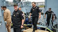 Three sailors in dark blue working uniforms.