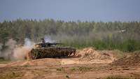 Ein Panzer startet einen Lenkflugkörper. Das Geschoss entweicht gerade der Kanonenmündung.