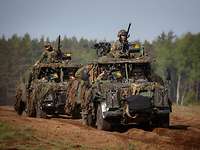 Die Infanterie der Niederlande Zwei offene Geländewagen fahren voll besetzt mit Soldaten durchs Gelände.