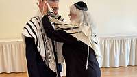 Eine Rabbinerin hängt einem Rabbiner einen Gebetsmantel um 