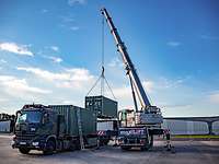 Ein Kran hievt einen Container auf einen Lkw