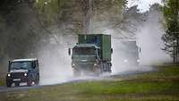 Bundeswehrlastkraftwagen fahren auf einer staubigen Straße