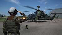 Ein Soldat steht vor dem Hubschrauber und grüßt militärisch.
