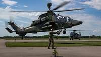 Ein Hubschrauber startet schnell mit deutlicher Querneigung, einer steht im Hintergrund.