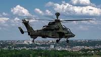 Ein Hubschrauber fliegt über eine Stadt mit Parks.