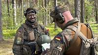 Ein Offizier steht im Wald und weist seinen Gruppenführer ein