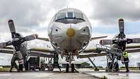 The front view of a large gray airplane. It's on an airfield.