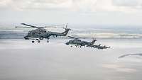 Several gray helicopters fly in formation in the sky.