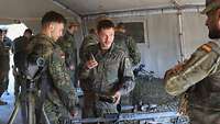 Zwei Soldaten schauen sich ein Präzisionsgewehr des spanischen Kontingents an. Ein Soldat hält eine Patrone hoch.