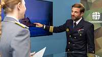 Eine Soldatin interviewt einen Soldaten, der auf ein U-Boot-Bild auf einem Monitor zeigt