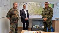 Zwei Soldaten und ein Mann im Anzug stehen vor einer Landkarte