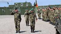 Drei Soldaten laufen an einer angetretenen Formation entlang