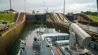 Ein graues Kriegsschiff passiert eine Schleuse.