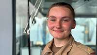 Porträtbild einer jungen Soldatin im Inneren eines Schiffs.