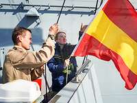 Zwei Soldaten hissen eine rot-gelb gestreifte Flagge.