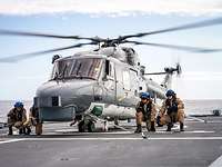 4 Soldaten sind abgehockt neben einem Militärhubschrauber