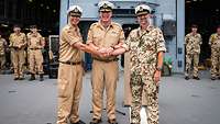 Zwei Marinesoldaten reichen sich die Hand. Ein dritter Marinesoldat hält seine Hand über deren.