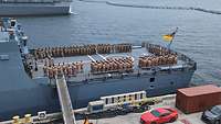 Zahlreiche Soldaten stehen in Formation auf einem Flugdeck