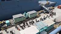 Zahlreiche Soldaten gehen an Bord eines Schiffes.
