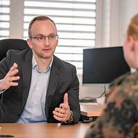 Eine Person sitzt einer Soldatin in einem Büro gegenüber und erklärt ihr etwas