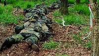 Ungeliebte Gangart Mehrere Soldaten gleiten hintereinander über den Waldboden