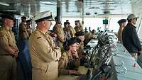 Zahlreiche Soldaten stehen in der Brücke eines Kriegsschiffs.