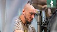 Ein Soldat kniet vor einer technischen Anlage und kontrolliert die Werte
