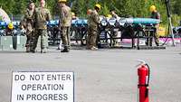 US and German soldiers work together on the assembly of practice bombs. 
