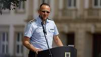 Ein Soldat spricht im Freien an einem Rednerpult.