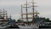 Zwei weiße Segelschiffe liegen in einem Hafen